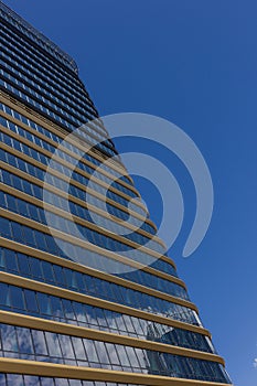 A close-up of a tall skyscraper corner against the sky. Glass background with sky reflection
