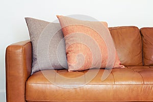 Close up of tan leather sofa with linen cushions