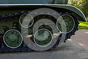 Close-up of the tank chassis. The iron wheels and tracks of the tank`s undercarriage are painted green and black