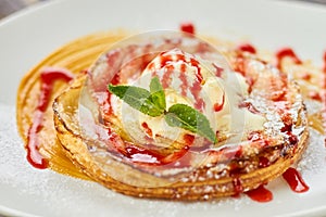 Close up tart with ice cream, mint and poured red sauce.