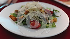 Close up of tasty classic salad cezar with tomato, chicken, mozzarella cheese.