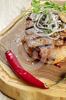 Close up on tasty Grilled Pork neck served on pita bread with onion, microgreen and hot pepper. Wooden background. Copy space.