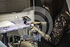Close up tattooer hands changing tattoo machinery needle