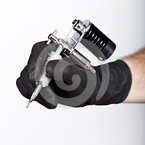 Close-up of Tattooist hands in black gloves with tattoo machine photo