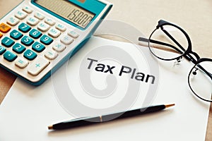 Close up tax planning word on paper with calculator, pen and eye glasses place on the wooden table