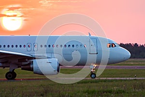 Close-up taxiing a white passenger airplane against the setting sun