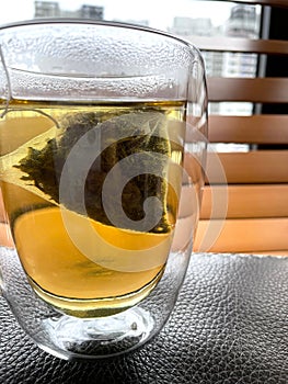 Close-up of tea in double walled glass with blinds background