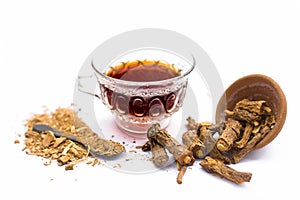 Close up of tea of Indian sarsaparilla or nnanari in a glass cup along with raw sarsaparilla and its powder. photo