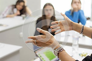 Close-up of teachers hand while teaching lessons in classroom to students, selective focus