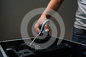 Close-up of technician hand using scissors to cut cable inside desktop computer, performing maintenance or repair work