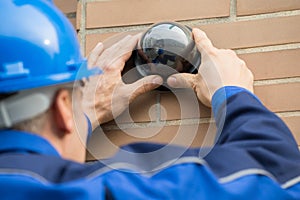 Close-up Of Technician Installing Camera In Building