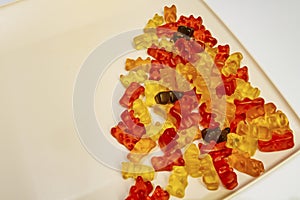 Teddy bear figured and colorful jelly beans in plate on white background.