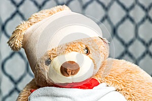 Close up of a teddy bear    wrapped in a head bandage and towel