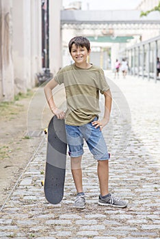 A teenage boy carrying skateboard and smiling