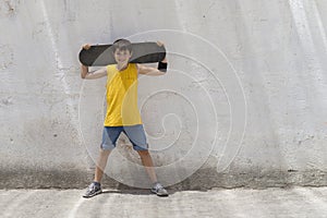 A teenage boy carrying skateboard and smiling