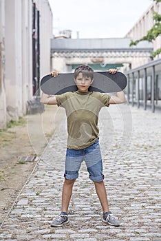 A teenage boy carrying skateboard and smiling