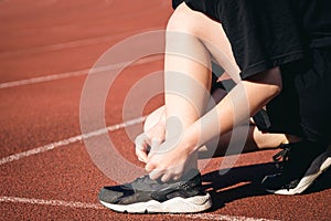 Close-up, teenage girl tying her shoelaces at the stadium before jogging.