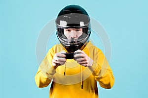 Close-up of a teenager in a black motorcycle helmet and with a joystick in his hands