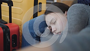 Close-up of teenager girl sleeping next to mom on the chairs in the waiting room of the airport. The delay of the flight