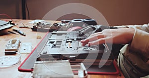 Close-up. A teenager sits thoughtfully over a disassembled laptop. Careful attitude to technology. Repair and