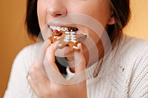 Close-up of teeth biting off freshly baked gingerbread cookie.