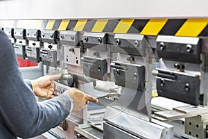 Close up teeth of the semi automatic hydraulic bending machine and the technician`s hands catch the metal sheet or the workpiece