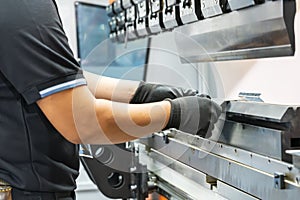 Close up teeth of the semi automatic hydraulic bending machine and the technician`s hands catch the metal sheet or the workpiece