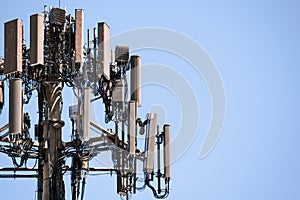 Close up of telecommunications cell phone tower with wireless communication antennas; blue sky background and copy space on the