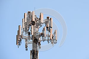 Close up of telecommunications cell phone tower with wireless communication antennas; blue sky background and copy space on the