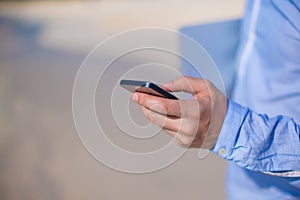 Close up telephone in male hand at tropical beach