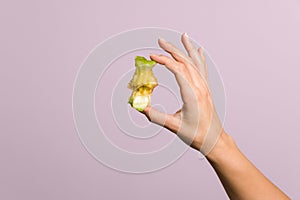 Close up tender female hand gently holding an apple core over pastel pink background. healthy food concept