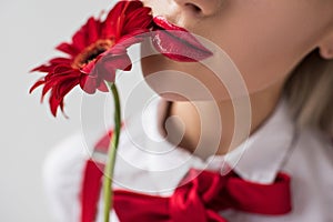 close up of tender girl with red lipstick and red gerbera flower,