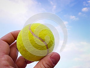 Close-up of  tennis ball in a man  hand agains blue sky