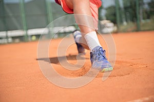 Close up of tennis player glide on the court. Sunny day.