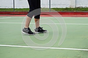 Close up of tennis player legs with black shoe playing on tennis court.