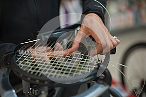 Close up of tennis stringer hands doing racket stringing