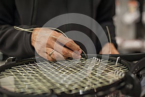 Close up of tennis stringer hands doing racket stringing