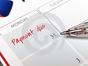 Close up text payment due written on calendar with a pen.