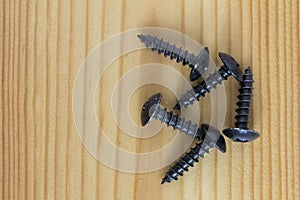 Close up texture of black metal screws pile, black iron screws on a wooden table