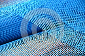 Close-up texture of a blue reinforcing mesh rolled up in a roll. Building resource for reinforcing walls in the process of their