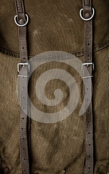 Close-up texture of a canvas fabric backpack. Leather straps and metal buckles. Vintage khaki back
