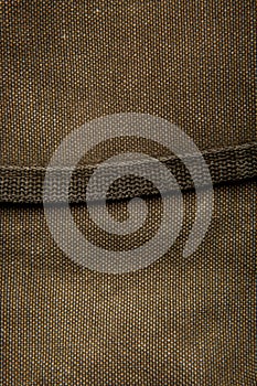 Close-up texture of a canvas fabric backpack. Leather straps and metal buckles. Vintage khaki back