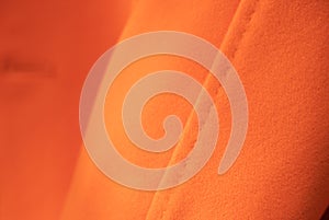 Close up texture of luxurious orange cashmere fabric on coat.