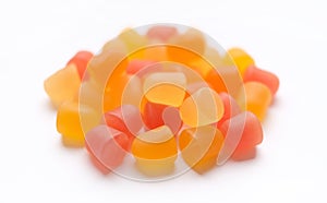 Close-up texture of orange and yellow multivitamin gummies in the form of bears on white background.