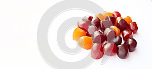 Close-up texture of red, orange and purple multivitamin gummies on white background. Healthy lifestyle concept