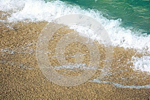 close up texture of the sea wave rolling on to the golden sandy beach