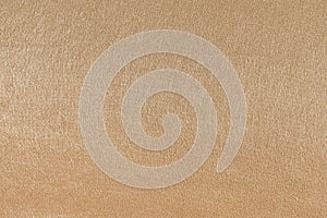 Close-up texture of a shiny beige fabric made of synthetics. Fabric for sewing suits, clothes. Elegant background for your design