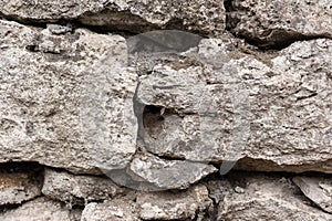 Close-up textured background is an irregular natural stone wall made of different stones without a cement-type bonding