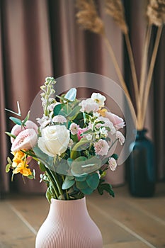 Close-up a textured pink vase holding a vibrant bouquet of assorted flowers