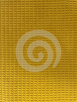 Close-up of textured yellow fabric with a soft grid pattern.